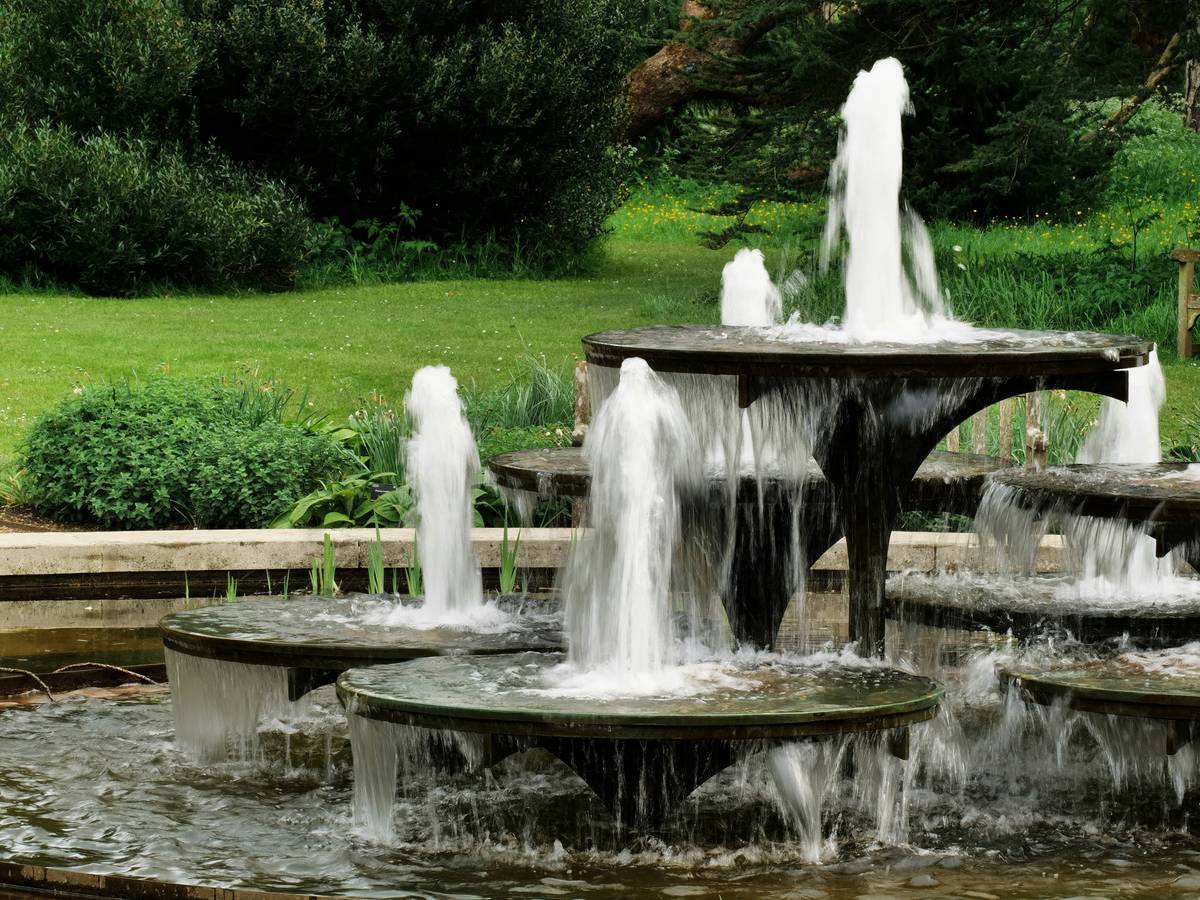 Stone-tiered outdoor fountains and waterfalls with cascading water in a suburban backyard
